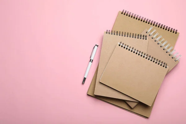 Cuadernos kraft con estilo y pluma sobre fondo rosa, la colocación plana. Sp — Foto de Stock