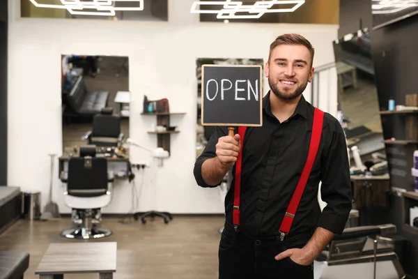 Young business owner holding OPEN sign in his barber shop — 스톡 사진