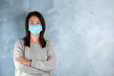 Yüzü açık mavi arka planda tek kullanımlık maskeli bir kadın. Metin için boşluk
