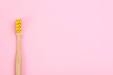 Pembe arka planda bambudan yapılmış diş fırçası, üst manzara. Metin için boşluk