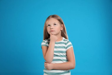 Açık mavi arka planda duygusal küçük kız portresi