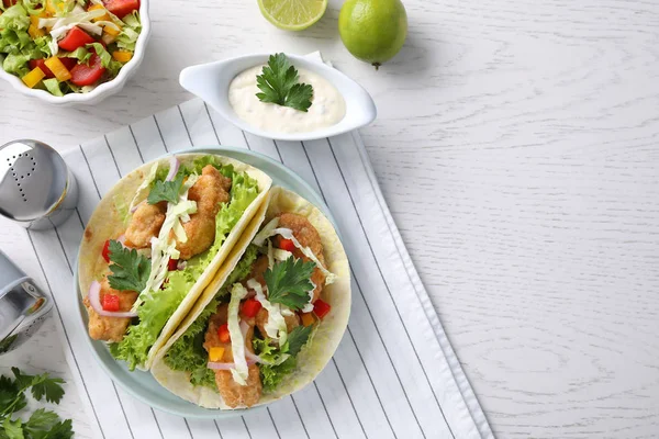 Yummy fish tacos served on white wooden table, flat lay. Space for text