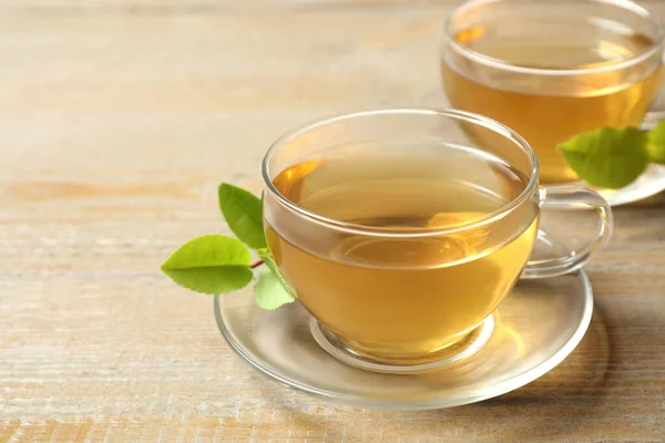 Tassen Mit Grünem Tee Und Blättern Auf Holztisch — Stockfoto