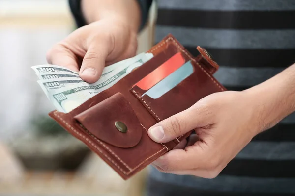Hombre poniendo dinero en la cartera en el fondo borroso, primer plano —  Fotos de Stock