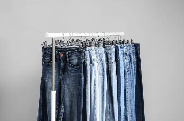グレーの背景に異なるジーンズを持つラック — ストック写真
