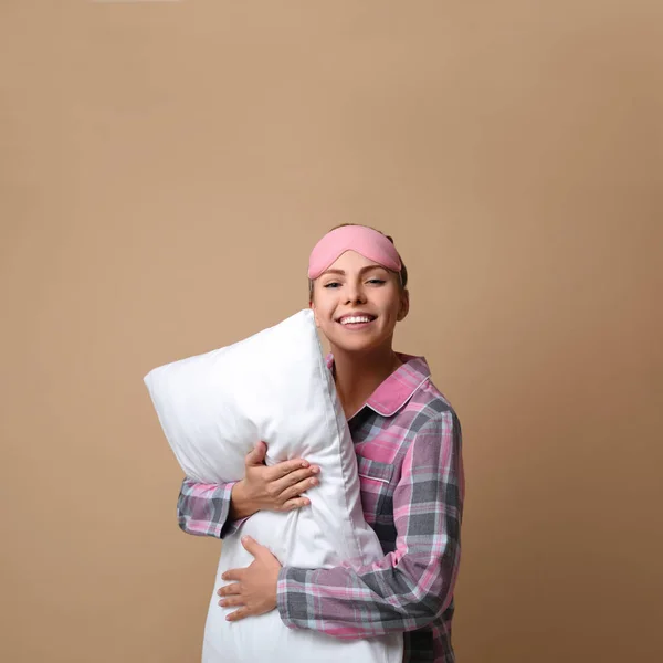 Beautiful woman with pillow on beige background. Bedtime — ストック写真