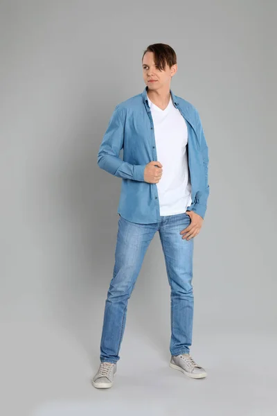 Ung man i snygga jeans på grå bakgrund — Stockfoto