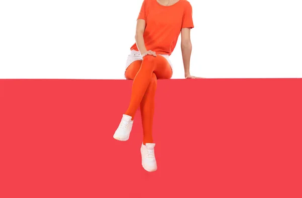 Женщина в красных колготках и стильной обуви сидит на спине цвета — стоковое фото