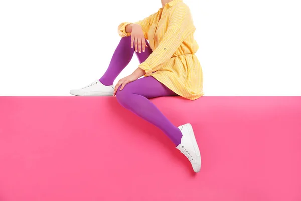 Frau mit hellen Strumpfhosen und eleganten Schuhen sitzt auf Farbe b — Stockfoto