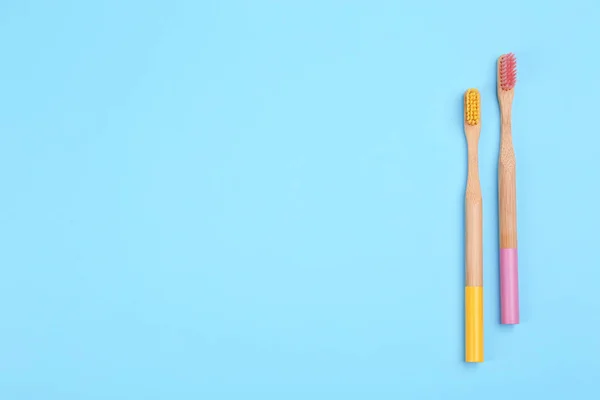 Escovas de dentes feitas de bambu no fundo azul claro, flat lay . — Fotografia de Stock