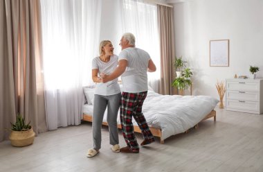 Mutlu olgun çift yatak odasında dans ediyor.