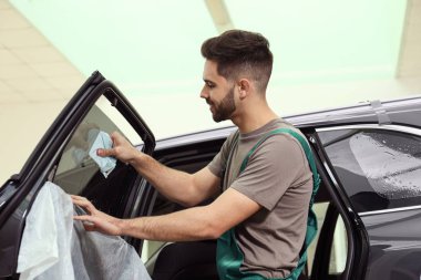 Atölyede renkli araba camlarını yıkayan bir işçi