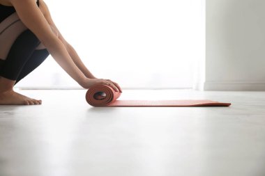 Yoga stüdyosunda paspası yerde yuvarlanan bir kadın.