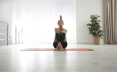 Kadın yoga stüdyosunda kartal asana alıştırması yapıyor. Garudasana pozu