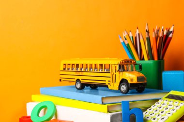 Okul otobüsü modeli ve turuncu arka planda kırtasiye malzemesi. Aktarım 