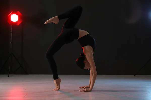 Jovem acrobata profissional exercitando no estúdio escuro — Fotografia de Stock