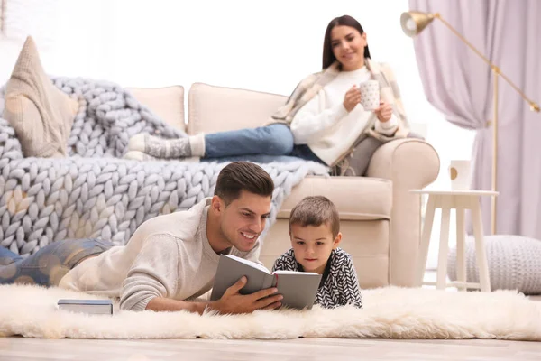 Far och hans son läser böcker medan mor vilar på soffan på — Stockfoto
