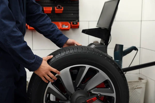 Homem trabalhando com máquina de balanceamento de rodas ao serviço de pneus, closeu — Fotografia de Stock