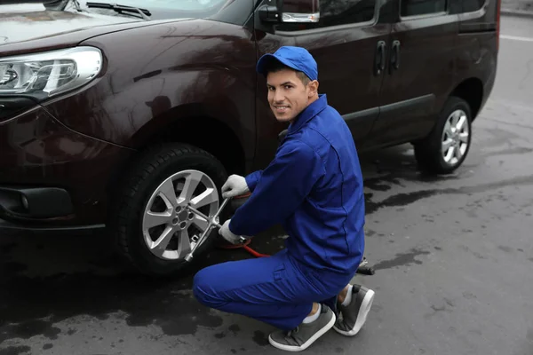 Trabalhador mudando roda de carro no serviço de pneus — Fotografia de Stock