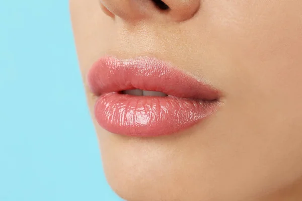 ライトブルーの背景に美しいフル唇を持つ女性,クローズアップ — ストック写真