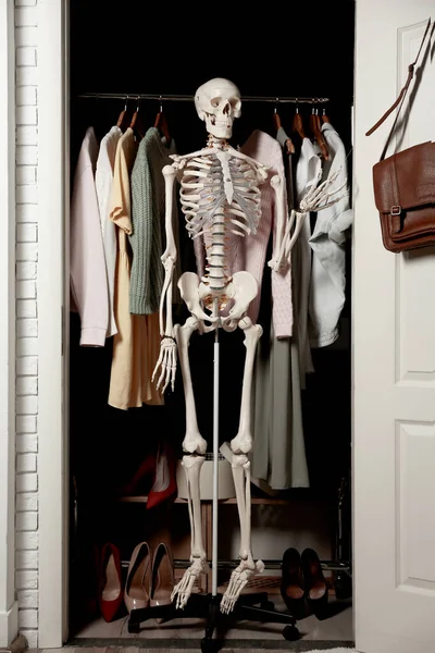 Artificial human skeleton model among clothes in wardrobe room — Stock Photo, Image