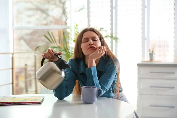 Сонная молодая женщина наливает кофе в чашку дома утром — стоковое фото