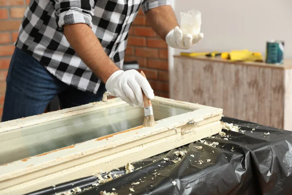 Man reparerar gamla skadade fönster vid bordet inomhus, närbild — Stockfoto