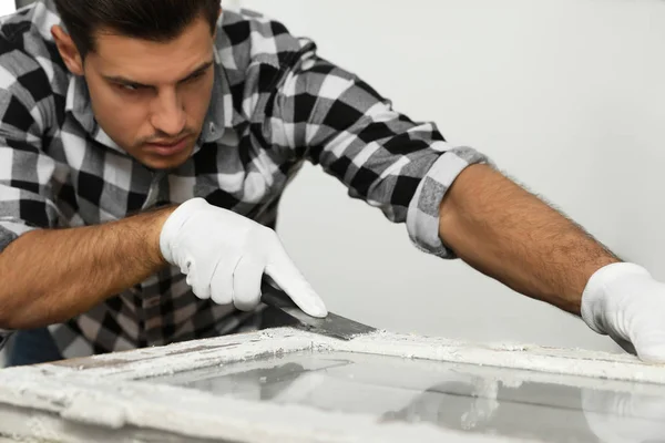 Man reparerar gamla skadade fönster vid bordet inomhus — Stockfoto