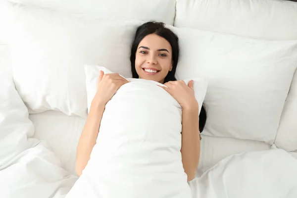 Junge Frau mit Kopfkissen im Bett, Draufsicht. fauler Morgen — Stockfoto