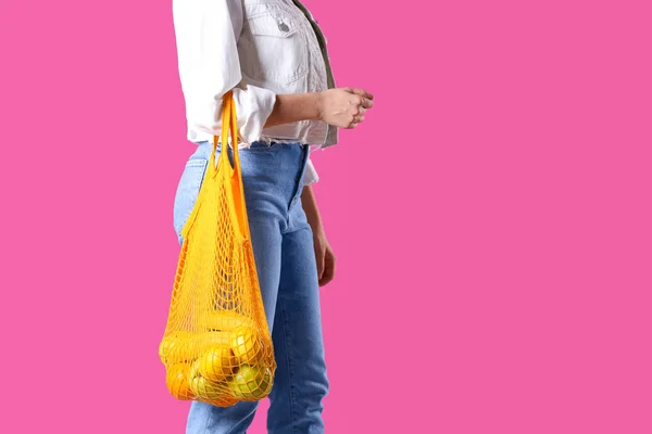 Mulher segurando saco de rede com frutas no fundo rosa, close-up. S — Fotografia de Stock