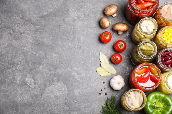 Farklı turşulu sebzelerle dolu cam kavanozlar gri masada, düz. — Stok fotoğraf
