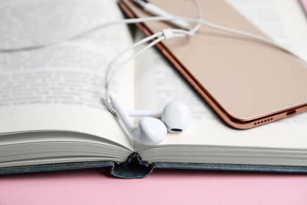 Βιβλίο, ακουστικά και smartphone σε ροζ φόντο, closeup — Φωτογραφία Αρχείου