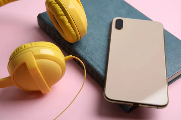 Boek, moderne koptelefoon en smartphone op roze achtergrond, sluiten — Stockfoto