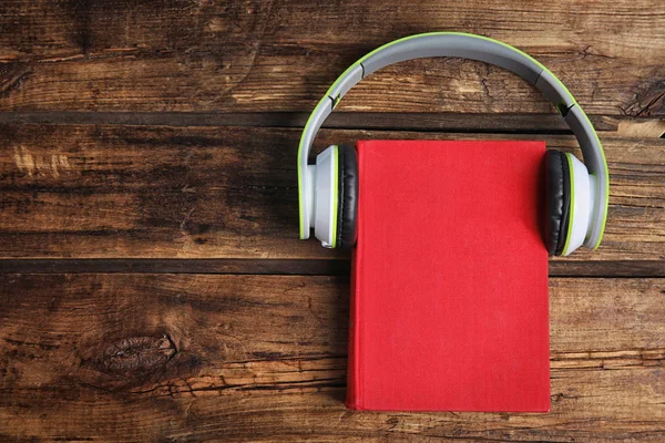 Libro y auriculares modernos en mesa de madera, vista superior. Espacio para —  Fotos de Stock