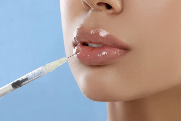 若い女性取得唇注射の上にライトブルーの背景 クローズアップ — ストック写真