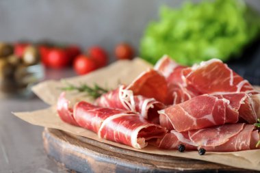 Gri masada lezzetli prosciutto dilimleri, yakın plan.
