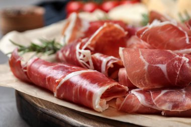 Gri masada lezzetli prosciutto dilimleri, yakın plan.