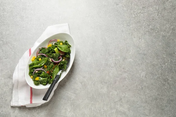 Tasty fresh kale salad on light grey table, top view