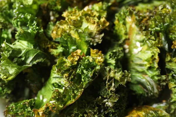 Baked tasty kale chips as background, closeup