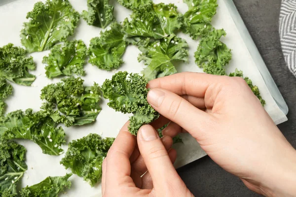 Kvinna Förbereder Välsmakande Grönkålschips Vid Grått Bord Ovanifrån — Stockfoto