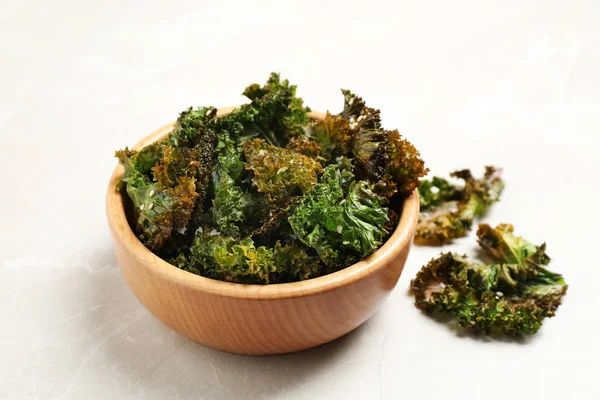 Tasty baked kale chips on grey marble table