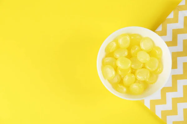 Deliciosas gotas de limón en un tazón sobre fondo amarillo, la puesta plana. Sp — Foto de Stock