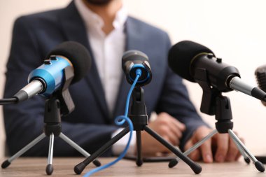 Businessman giving interview at table with microphones, closeup. Journalist conference clipart