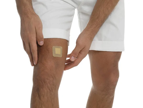 Homem com colagem de gesso no joelho contra fundo branco, clos — Fotografia de Stock