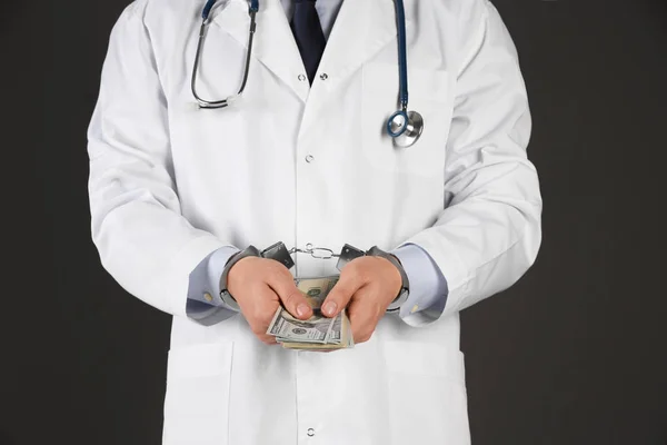 Dokter in handboeien met steekpenningen op zwarte achtergrond, close-up. Cor — Stockfoto