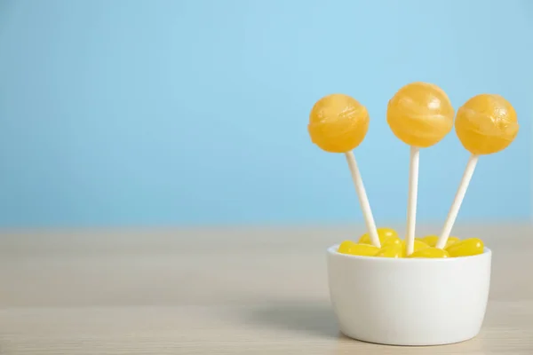 Different lemon candies on wooden table. Space for text