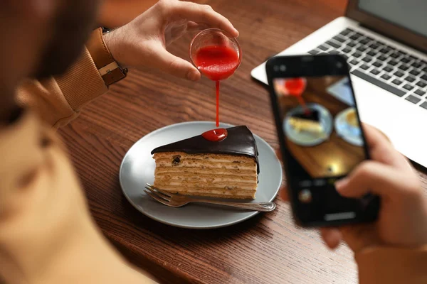 Male blogger taking photo of dessert at table in cafe, closeup — Stock Photo, Image