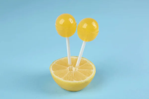 Fresh lemon with yellow lollipops on light blue background — 스톡 사진