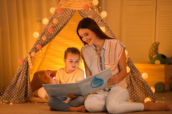 Mãe e filha com lanterna livro de leitura em casa — Fotografia de Stock