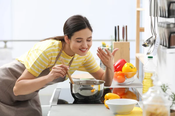 Молодая женщина готовит вкусный суп на кухне — стоковое фото